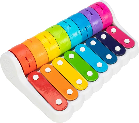 A colorful Rock 'N Roller Piano by Fat Brain, featuring vibrant xylophone bars in a variety of colors including red, orange, yellow, green, blue, and purple, all mounted on a white base. The design emphasizes musical play for children with easy-to-hit mallets.