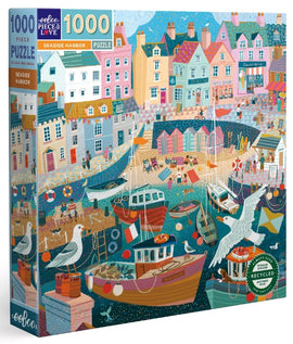 The Seaside Harbor jigsaw puzzle by Eeboo features a colorful illustration of a coastal scene, with vibrant houses lining a busy harbor filled with boats. Seagulls fly above the docks where people enjoy the seaside. Perfect for puzzlers who appreciate detailed artwork.