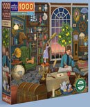 The Alchemist's Library jigsaw puzzle by Eeboo features a richly detailed illustration of an alchemist's study, showcasing a diverse collection of books, globes, telescopes, and other scientific instruments. A child looks through a telescope while a thoughtful alchemist writes at a cluttered desk. The surroundings include a cozy green chair, a cat lounging nearby, and various decorative items, all set against a backdrop of a large window revealing a twilight sky.