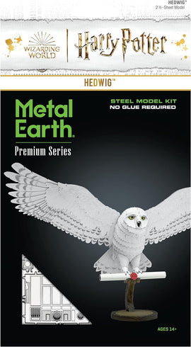 The Premium S: Hedwig DIY model kit by Fascinations features a beautifully detailed white owl, standing on a wooden base, holding a scroll. The model is made from steel with intricate feather designs and is part of the Harry Potter franchise. It comes on a 2.5-sheet model design that requires no glue for assembly, suitable for ages 14 and up.