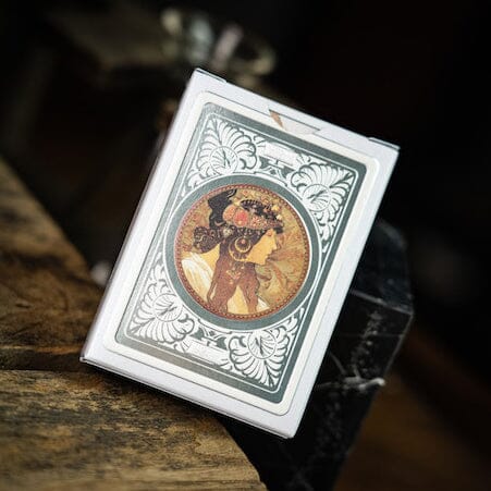 A beautifully designed game called Mucha Princess Hyacinth Silver by TCC. The game features a vintage-inspired illustration of a woman adorned with floral elements. The packaging is elegantly decorated with intricate borders, showcasing the art style reminiscent of Alphonse Mucha. Ideal for art lovers and board game enthusiasts alike, this collectible item adds a touch of elegance to any game collection.