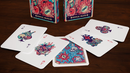 A close-up view of the Mystical Pirates Playing Cards spread out on a wooden table. The deck features colorful, whimsical illustrations of skeletons, octopuses, and pirate-themed designs on both the face and back of the cards. The card backs are vibrant and eye-catching, while a portion of the decorative box is also visible in the background, adding to the enchanting theme.