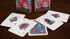 A close-up view of the Mystical Pirates Playing Cards spread out on a wooden table. The deck features colorful, whimsical illustrations of skeletons, octopuses, and pirate-themed designs on both the face and back of the cards. The card backs are vibrant and eye-catching, while a portion of the decorative box is also visible in the background, adding to the enchanting theme.