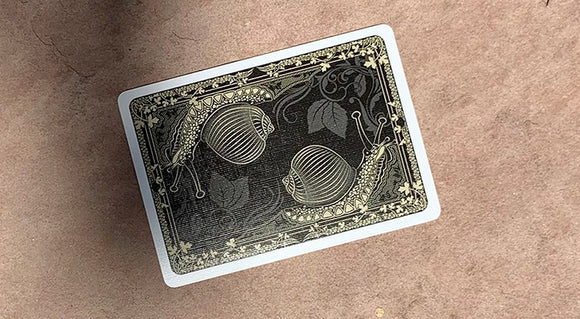 Bicycle Snail (Orange) Playing Cards featuring a unique design of snails and decorative elements on a black background, produced by US Playing Card Co. Ideal for card games and collectors.