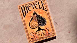 Bicycle Snail (Orange) Playing Cards packaged in an intricately designed box featuring a stylized snail and black leaf artwork against an orange background.