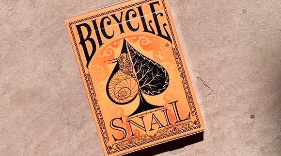 Bicycle Snail (Orange) Playing Cards packaged in an intricately designed box featuring a stylized snail and black leaf artwork against an orange background.
