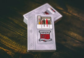 A stylish deck of Nerds Playing Cards by Midnight Cards, featuring a sleek design with vibrant colors and intricate detailing on the front. The packaging displays various tools and accessories that hint at a playful and engaging theme, perfect for game nights and gatherings. The cards are neatly packaged, showcasing creativity and a fun twist on traditional playing cards.