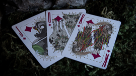 A close-up view of three Under the Moon playing cards by Jocu, featuring unique illustrations of animals adorned with floral crowns. The cards displayed are the Jack, Queen, and King, highlighted against a grassy background.
