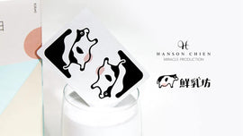 A stylish set of Pure Milk Playing Cards by Hanson Chien Production Co. The cards feature a fun cow design on one face, highlighting their playful theme. The image showcases the cards beside a glass of milk and a creatively designed box, emphasizing their unique concept based on a dairy theme.