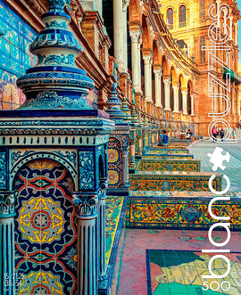 A jigsaw puzzle box featuring an intricate design of colorful Spanish tiles. The artwork showcases vibrant blue, yellow, and intricate geometric patterns arranged along columns, evoking the charm of Spanish architecture. The scene captures the essence of a sunny day in Spain, highlighting the beauty of tiled surfaces and detailed craftsmanship. The box is designed by Blanc Puzzles and includes 500 pieces for a challenging and enjoyable puzzle experience.