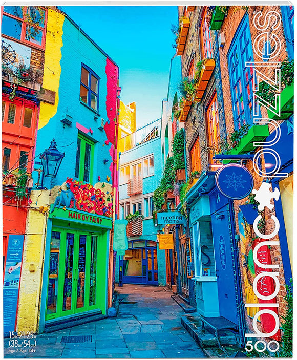 A vibrant jigsaw puzzle image depicting a colorful narrow street in London, featuring brightly painted buildings in hues of blue, yellow, and pink. A shop named 'Hair by Fairy' is prominently displayed, along with hanging plants and outdoor lighting. The scene captures the charm of urban life with colorful façades and a clear blue sky in the background.
