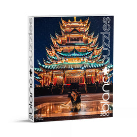 A vibrant jigsaw puzzle box featuring the stunning Chongqing Chinese Temple illuminated at night. The colorful traditional architecture is adorned with intricate details against a starry sky, and a person sits nearby, adding a human touch to the serene scene. This 500-piece puzzle by Blanc Puzzles invites puzzlers to recreate this enchanting moment.