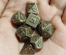 A close-up of a hand holding a set of 10MM ancient gold metal RPG dice. The dice feature engraved numbers with a textured surface, showcasing a classic and vintage design. There are multiple shapes including a d20, d12, d10, d8, d6, and d4, all in an ancient gold finish, ideal for role-playing games and tabletop adventures.
