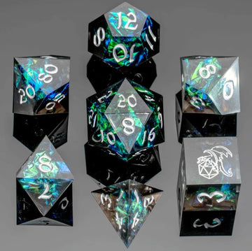 A set of eight black sharp edge dice featuring intricate designs and shimmering green and blue accents. The dice include various shapes such as d4, d6, d8, d10, d12, and d20, each showing numbers in white. The collection is placed on a sleek black surface, enhancing their vibrant colors and polished surfaces.