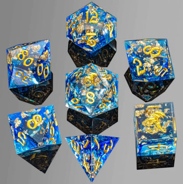 A set of Blue Gold Foil Sharp Edge RPG Dice from Hymgho, featuring a dazzling blue resin with gold foil accents. The set includes various polyhedral dice, showcasing numbers in bright gold against a shimmering background, ideal for tabletop role-playing games.