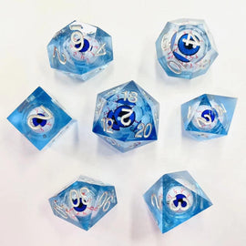 Set of seven RPG dice titled 'Always Watching Blue Eyes' by Hymgho. The dice feature a translucent blue design with intricate blue eye patterns and silver numbering, including shapes like d20, d12, d10, d8, d6, and d4, ideal for tabletop gaming.