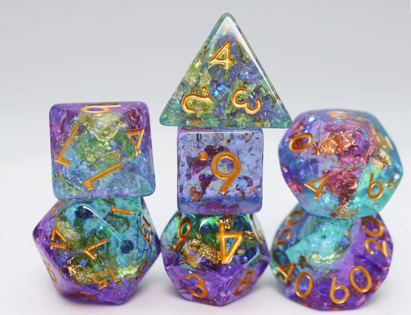A vibrant Reminisce RPG Dice Set by Foam Brain, featuring various polyhedral dice in shades of purple, blue, and green with golden numbers. The set includes a transparent tetrahedron, dodecahedron, and other shapes, stacked artistically to showcase their unique designs and colors, ideal for tabletop gaming enthusiasts.