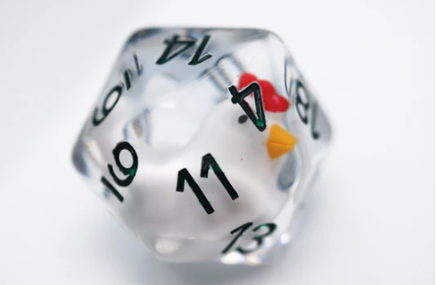 A 30mm Big Mama Hen D20 die, crafted by Foam Brain, featuring a playful design of a chicken inside a transparent polyhedral shape. The die has black numbers printed on its surfaces, adding a whimsical touch to gaming sessions.