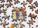 A collection of intricately designed wooden jigsaw puzzle pieces featuring vibrant colors and abstract patterns, with one piece prominently placed in the center. The artwork is inspired by the Cape Cod Pier, showcasing a beautiful blend of hues that create a stunning visual experience while assembling the puzzle.