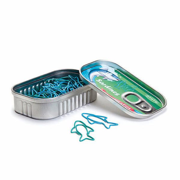 A tin can designed to resemble a sardine can, partially opened, revealing a collection of blue sardine-shaped paper clips inside. The lid features colorful graphics of a sardine swimming, making it a fun and quirky office accessory.