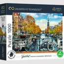 A high-quality jigsaw puzzle box featuring a picturesque autumn scene in Amsterdam, showcasing bicycles lined along a canal with orange and yellow trees, and a clock tower in the background.