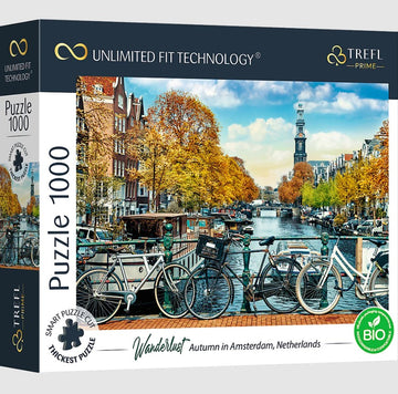 A high-quality jigsaw puzzle box featuring a picturesque autumn scene in Amsterdam, showcasing bicycles lined along a canal with orange and yellow trees, and a clock tower in the background.