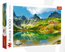 A jigsaw puzzle by Trefl featuring a scenic landscape titled 'Shelter Over Green Pond'. The image showcases a tranquil green pond surrounded by majestic mountains and a charming yellow house, under a bright blue sky with a few clouds. This 1000-piece puzzle captures the beauty of nature, making it perfect for puzzle enthusiasts and nature lovers alike.