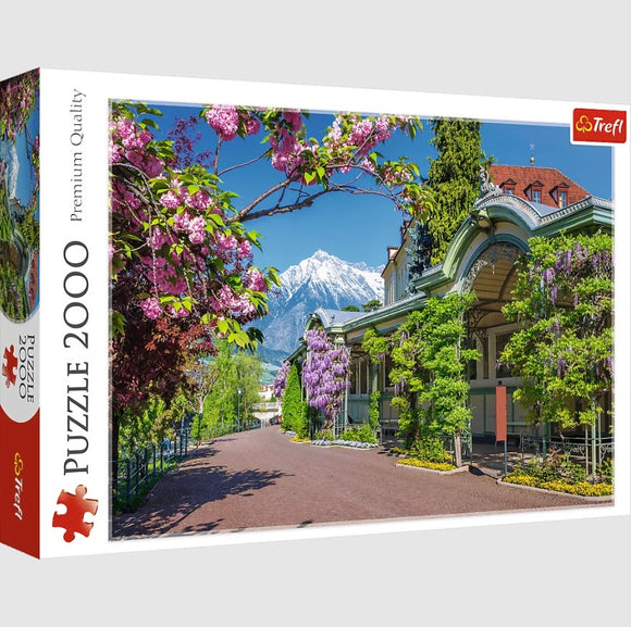 Trefl Jigsaw Puzzle featuring a stunning landscape of Merano, Italy, showcasing vibrant flowers and the majestic Alps in the background. The puzzle has 2000 pieces and emphasizes premium quality.