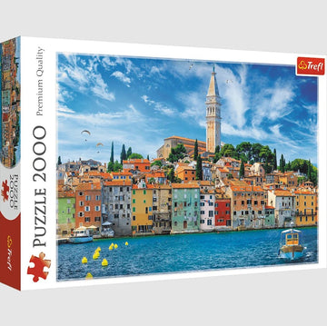Trefl 2000-piece jigsaw puzzle featuring a vibrant view of Rovinj, Croatia. The image showcases colorful buildings along the waterfront, with a tall bell tower and lush greenery in the background. Perfect for puzzle enthusiasts and lovers of scenic landscapes.