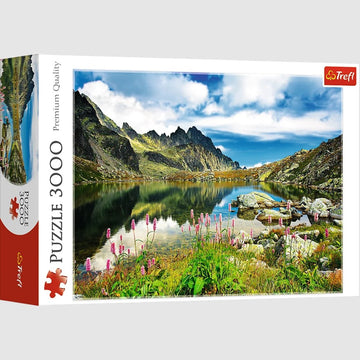 Trefl 3000-piece jigsaw puzzle featuring the scenic Starolesnianski Pond in the Tatras, Slovakia. The image depicts a stunning landscape with mountains, lush greenery, and reflections in the water, ideal for nature lovers and puzzle enthusiasts alike.