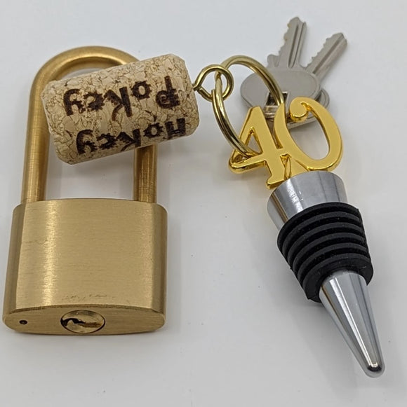 The HoKey PoKey Lock by Two Brass Monkeys is a creative mechanical puzzle that features a vintage brass padlock, a cork with 'HoKey PoKey' printed, and a decorative keychain with the number '40'. This unique item combines functionality and puzzle-solving elements, designed to engage users in a fun and challenging way.
