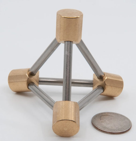 Tetrahedrane mechanical puzzle featuring a unique design with brass and steel components, arranged in a tetrahedral shape, alongside a quarter for size reference.