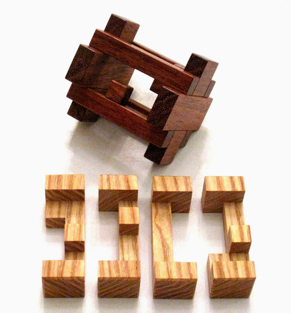 The Ice Pillar Mechanical Puzzle by Pelikan Puzzles features a complex design with interlocking wooden pieces. The main puzzle is made from dark wood with contrasting lighter wooden components displayed below. The arrangement challenges the mind, perfect for puzzle enthusiasts or as a decorative item.