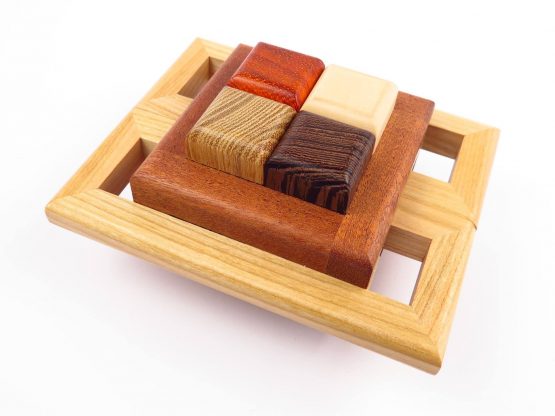 The Ultra mechanical puzzle by Pelikan Puzzles features a beautifully designed wooden base with four interlocking blocks made of different types of wood, showcasing rich textures and colors. This intricate puzzle encourages critical thinking and problem-solving skills while offering a tactile experience.