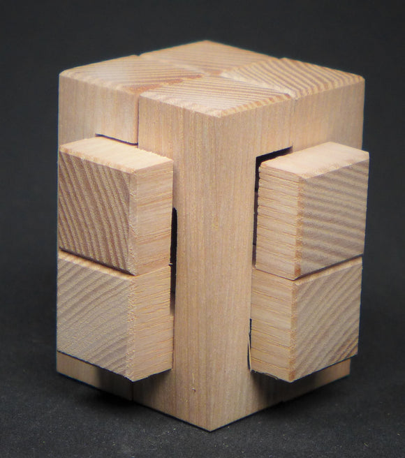 A wooden mechanical puzzle named 'Four in the Vice' by Arteludes. The puzzle features a cube structure with interlocking pieces and various textures on each side. It is made of light-colored wood with visible wood grain and smooth edges, resting on a dark background.