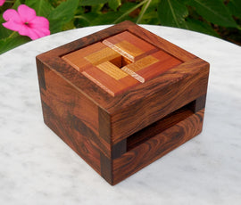 A beautifully crafted mechanical puzzle known as the Wheel Lock by WoodWonders. The puzzle features a wooden box design with intricate patterns and alternating wood tones, ideal for enhancing critical thinking while serving as an eye-catching decorative piece.