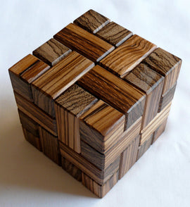 Stewart Coffin's Involute by WoodWonders is an intricately designed mechanical puzzle made of various polished wooden pieces. The puzzle features interlocking blocks that create a visually appealing three-dimensional structure. Its combination of natural wood tones enhances its aesthetic appeal, making it an engaging and challenging puzzle for both adults and children.