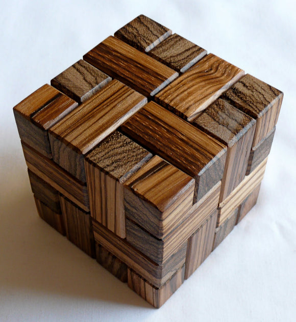 Stewart Coffin's Involute by WoodWonders is an intricately designed mechanical puzzle made of various polished wooden pieces. The puzzle features interlocking blocks that create a visually appealing three-dimensional structure. Its combination of natural wood tones enhances its aesthetic appeal, making it an engaging and challenging puzzle for both adults and children.