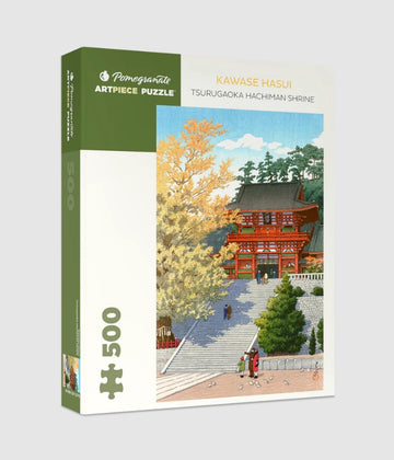 Pomegranate Artpiece Puzzle featuring the Tsurugaoka Hachiman Shrine, illustrated by Kawase Hasui. The puzzle box displays the vibrant artwork of the shrine surrounded by lush trees and colorful autumn leaves, with a serene setting inviting puzzle enthusiasts and art lovers alike.