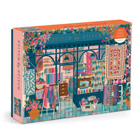 The 'Stitch by Stitch' jigsaw puzzle by Galison features a vibrant illustration of a cozy fabric shop. It includes colorful textiles, spools of thread, and a sewing machine, surrounded by flower pots and a playful cat, all designed in rich, detailed patterns.