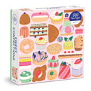 Sweet Confections jigsaw puzzle by Galison featuring a delightful assortment of desserts and sweets, including cupcakes, cakes, and pastries in vibrant colors. The puzzle consists of 500 pieces, showcasing intricate illustrations that invite puzzle enthusiasts to indulge their creativity and enjoy a fun and relaxing activity.