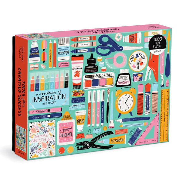Tools for Creative Success jigsaw puzzle by Galison featuring an artistic assortment of creative tools and motivational words. The puzzle showcases a vibrant design with icons like scissors, paints, glue, and encouraging phrases emphasizing themes of inspiration and perseverance, presented in a colorful palette of blue, pink, and green. This 1000-piece puzzle is both engaging and visually appealing, making it perfect for art enthusiasts and puzzle lovers alike.