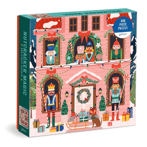 Colorful jigsaw puzzle box titled 'Nutcracker Magic' by Galison featuring a whimsical illustration of nutcrackers and holiday decorations. The box contains 500 pieces and showcases various festive characters in front of a pink house adorned with wreaths, lights, and gift boxes, perfect for holiday fun.