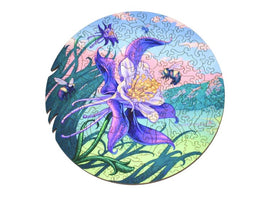 Colorful jigsaw puzzle featuring a vibrant illustration of the Colorado Columbine flower, surrounded by bees and a scenic background with blue skies and greenery. The puzzle showcases intricate cut-outs and a circular shape, perfect for enthusiasts of nature-themed art.