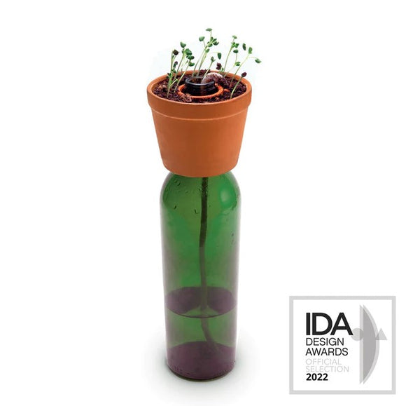 The Bottle Planter by Kikkerland is a unique and eco-friendly planter designed to repurpose a glass bottle. It features a small terracotta pot on top, holding soil and sprouts, while the green glass bottle below serves as a water reservoir. This innovative design promotes sustainable gardening by encouraging the recycling of bottles and features a charming aesthetic that enhances any indoor or outdoor space.