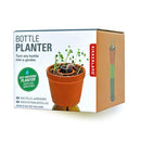 Kikkerland Bottle Planter packaging showcasing a self-watering planter that turns any bottle into a garden. The box has a clay pot with sprouts and highlights features like keeping soil moist. Seeds and soil not included.