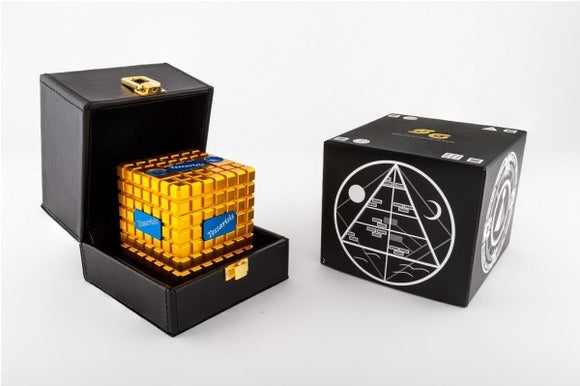 The Tessariss Gold & Blue Edition mechanical puzzle by Sonic Games. The puzzle, featuring a striking gold design, is displayed in an elegant black box. The packaging is adorned with intricate graphics and information about the puzzle, making it a beautiful addition to any collection.
