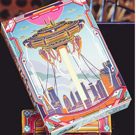 A colorful deck of playing cards titled 'Come (Aliens)', designed by King Star. The packaging features an artistic illustration of a spaceship hovering over a futuristic cityscape, with vibrant colors and intricate details that capture the essence of science fiction themes.