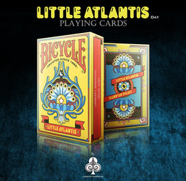 Bicycle Little Atlantis Day Playing Cards showcased in vibrant packaging, featuring colorful artistic designs and the logo of GAMblers Warehouse. The front side includes a whimsical illustration of an ornate sea motif, enhancing its visual appeal for card game enthusiasts.