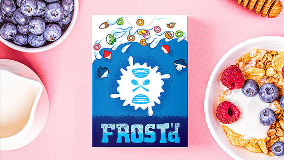 Frost'd Playing Cards by Howlin' Jack's displayed on a colorful background. The box features a vibrant blue design with playful graphics, including ice-inspired elements. Surrounding the box are fresh blueberries, raspberries, and cereal, suggesting a fun and casual gaming atmosphere.